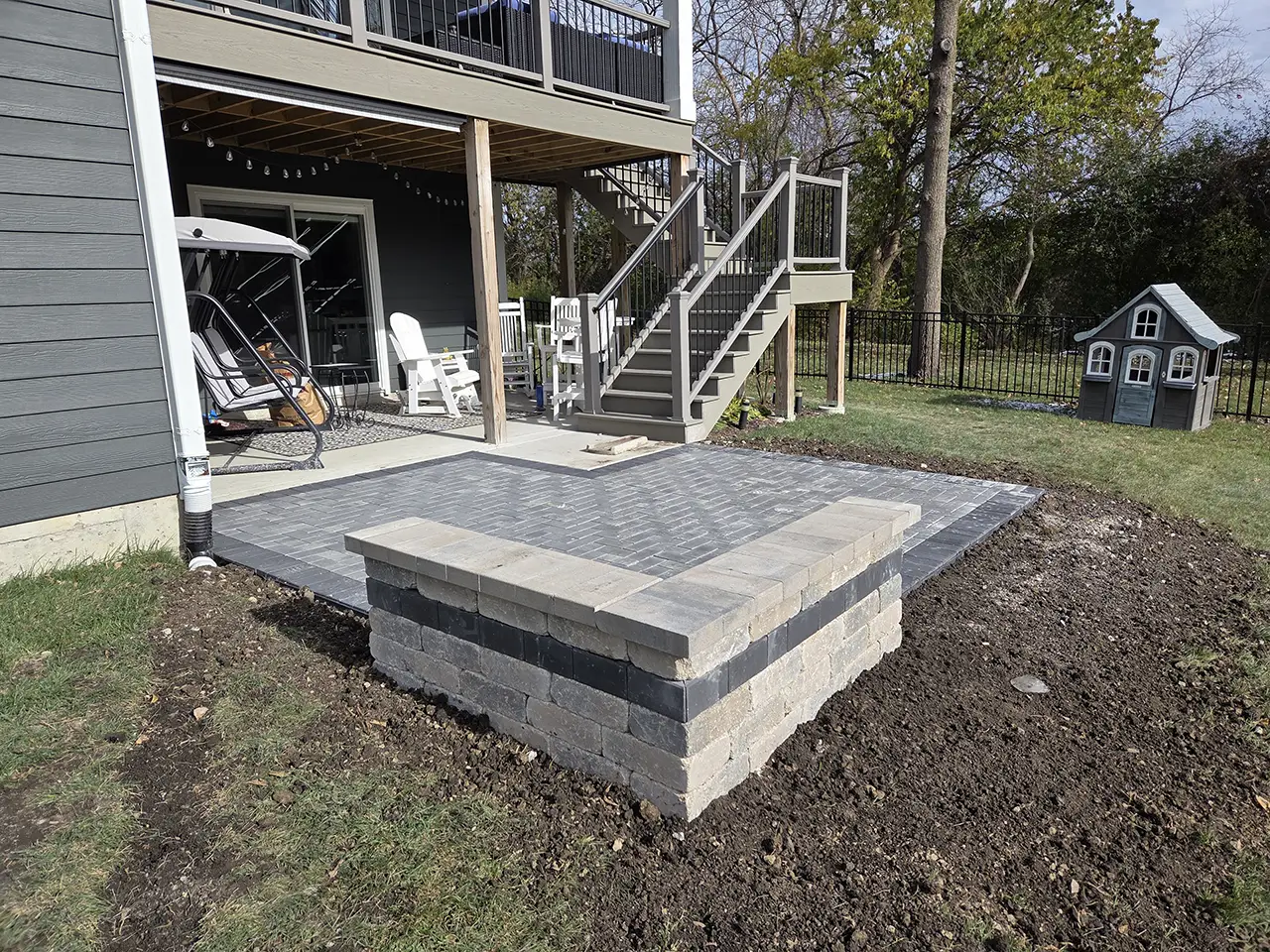 Brick paver patio with raised seating wall installed behind a residential home in Palatine, IL